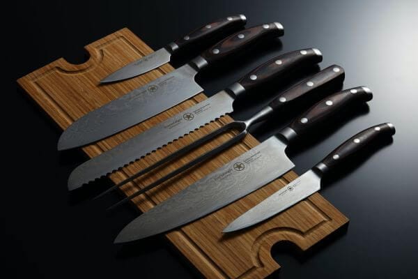 Set of Damascus kitchen knives on wooden board