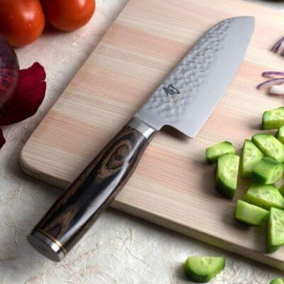 Santoku knife on cutting board with veggies that have been cut up